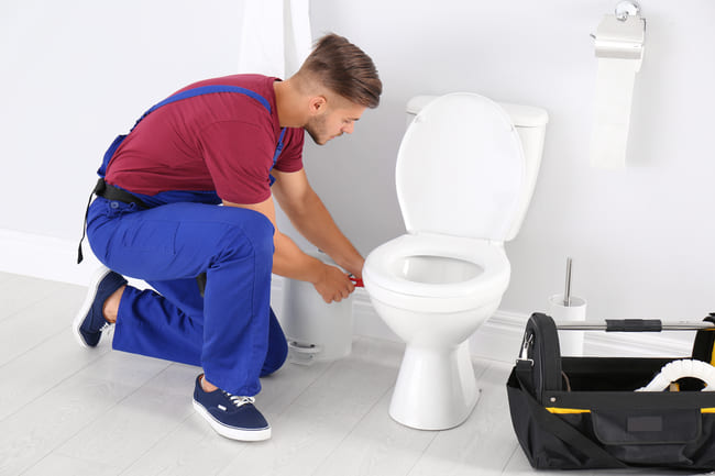 Artisan qui répare des toilettes