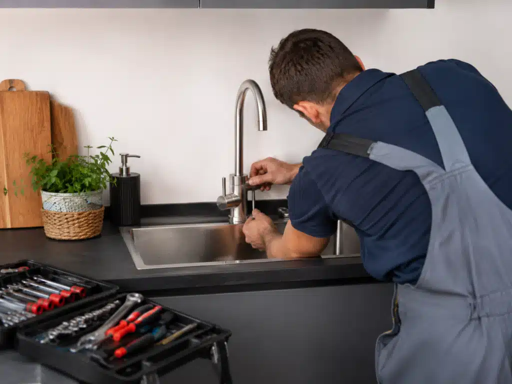 Plombier Nancy réparant un robinet de cuisine dans une installation résidentielle.
