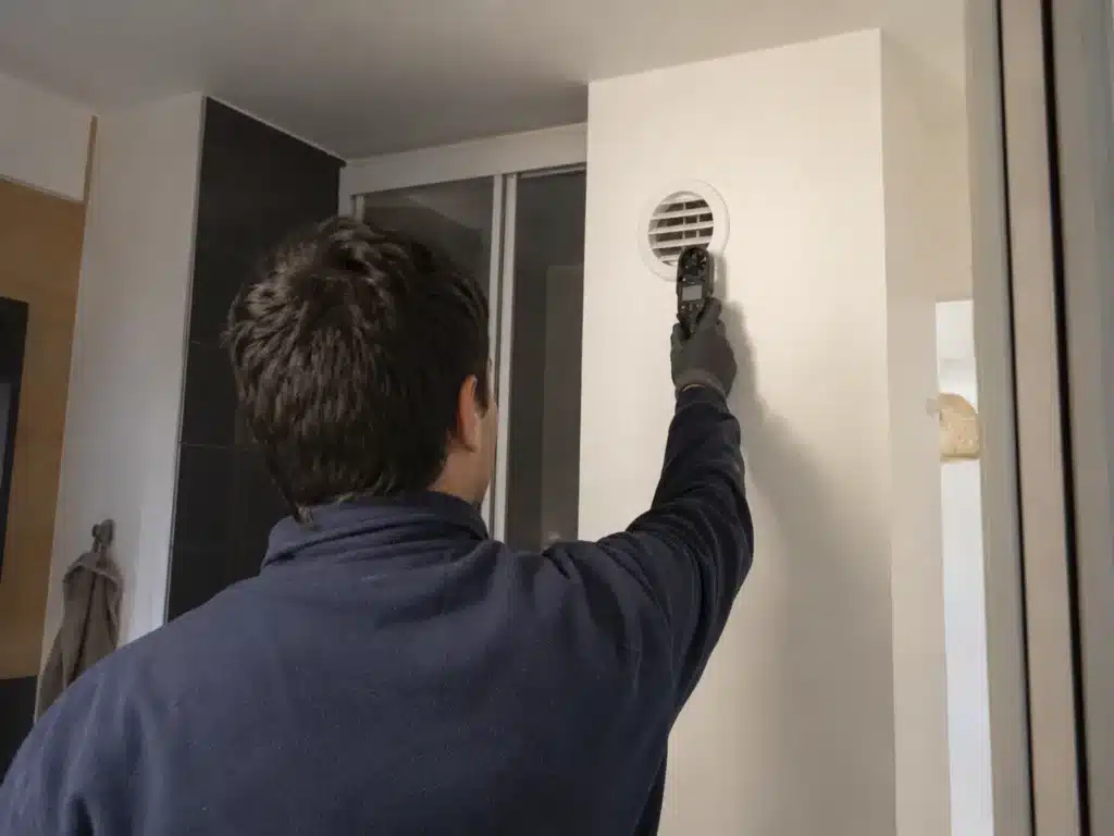 Installateur VMC mesurant le débit d’air d’une bouche de ventilation.
